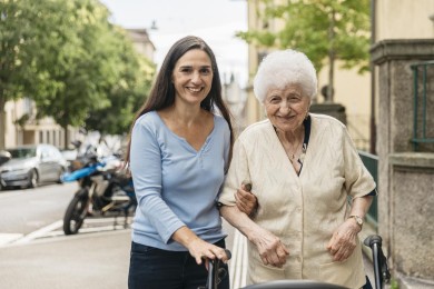 Ein Freiwillige hilft einer Seniorin beim Spaziergang