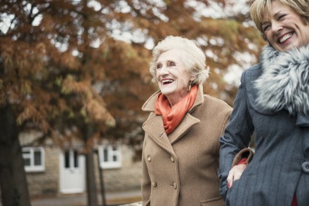 Eine jüngere Frau führt eine ältere Frau spazieren. 